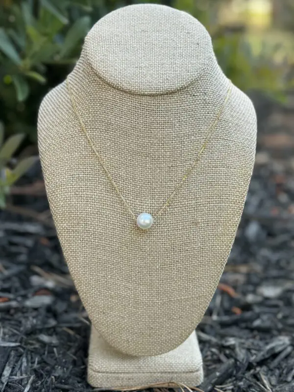 Gold chain necklace with single pearl pendant.