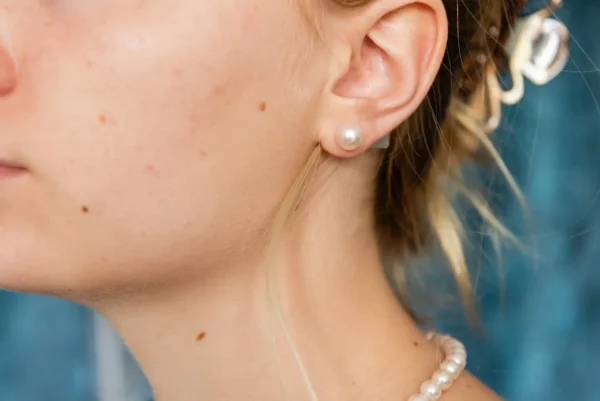 A woman wearing pearls and ear piercings.