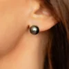 A woman wearing black pearl earrings.