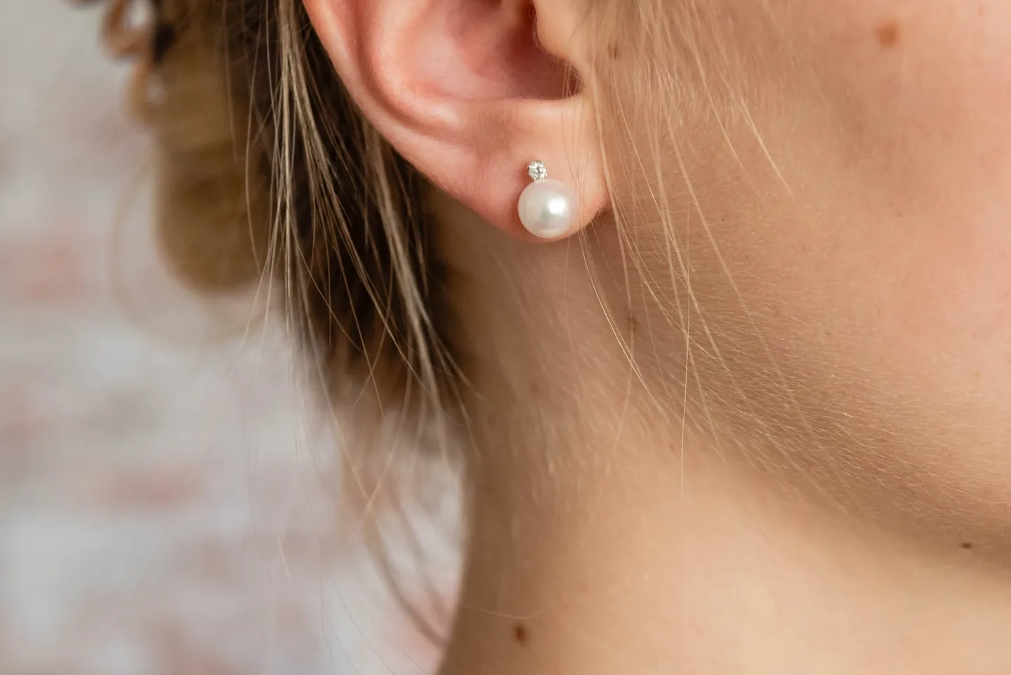 A woman wearing a pair of earrings with pearls.